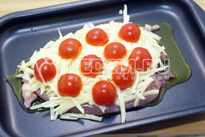 Выложить поверх отбивной картофель и половинки помидоров