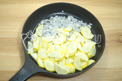 На сковороде разогреть растительное масло и добавить мелко нашинкованный лук и полукольцами нарезанные кабачки.