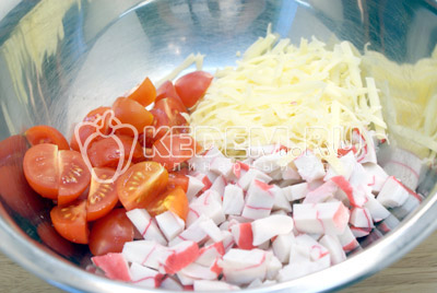 В миске смешать ломтиками нарезанное крабовое мясо, четвертинками нарезанные помидоры и тертый сыр