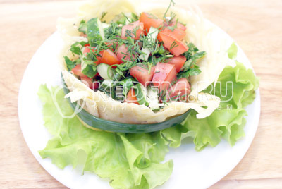Выложить салат в корзинку и украсить зеленью салата и лука
