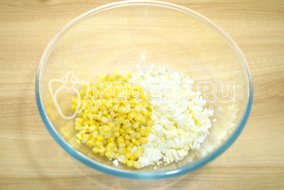 В миску мелкими кубиками нарезать яйца и добавить консервированную кукурузу.