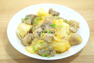 Тушеный картофель с мясом выложить на тарелки и посыпать мелко нашинкованным зеленым луком.