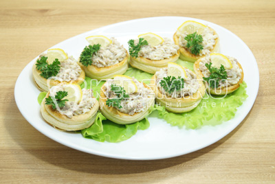 Выложить на блюдо с листьями салата, украсить зеленью и дольками лимона.