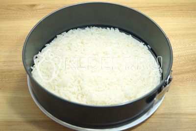 В сервировочное кольцо или разъемную форму для выпечки выложить первый слой отварного риса.