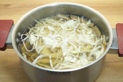 В кастрюлю с грибами сложить картофель и нашинкованную капусту. Варить 10-12 минут.