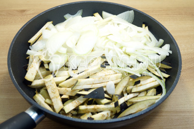 Баклажаны нарезать соломкой, лук полукольцами, выложить в сковороду с растительным маслом.