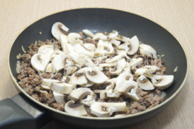 Добавить нарезанные грибы в сковороду и готовить еще 2-3 минуты. Посолить и поперчить по вкусу.