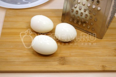 Три яйца отварить, остудить и очистить. Натереть отварные яйца на терке.