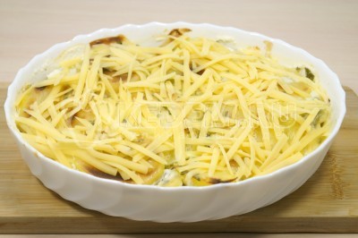 Вынуть картофель из духовки и посыпать сверху тертым сыром.