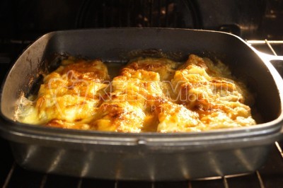 Запекать минтай с луком и сыром в духовке при 180 градусах Цельсия 25 минут.